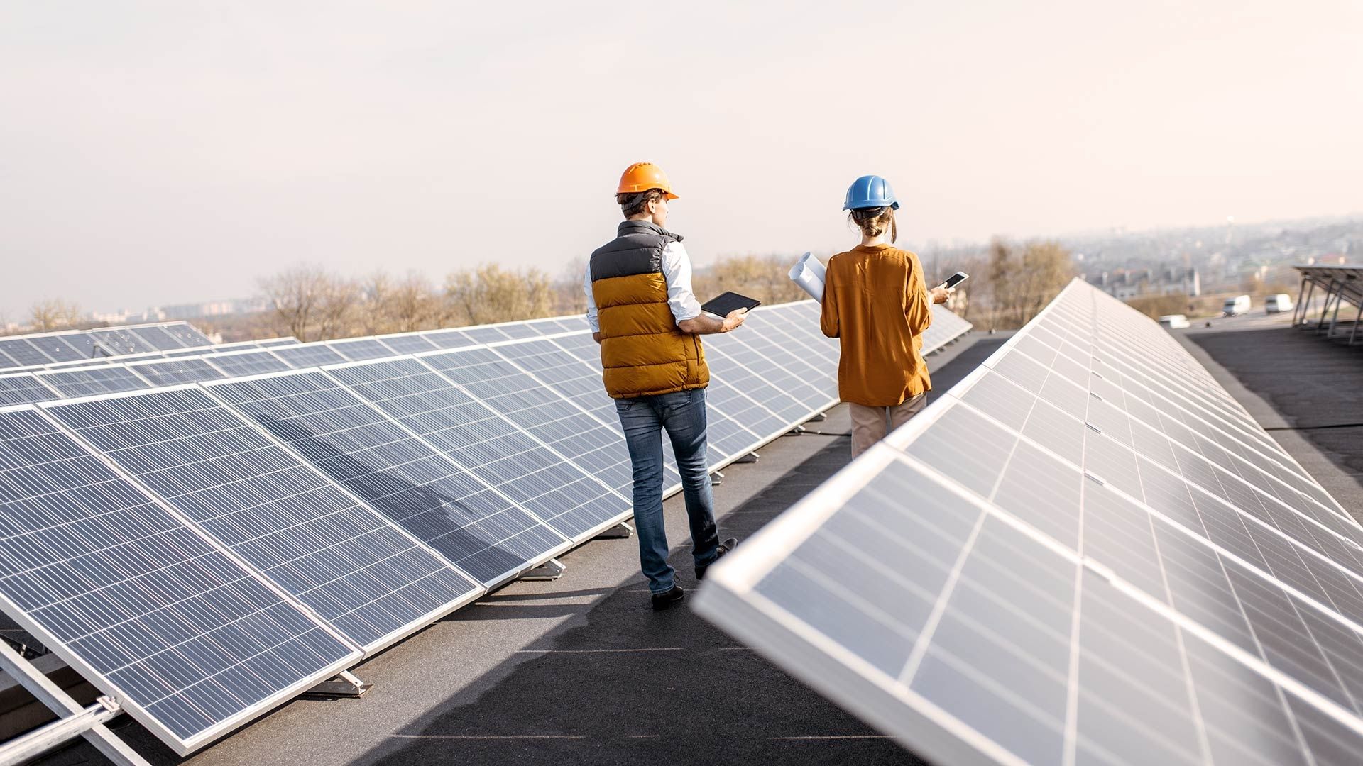 Zwei Arbeiter inspizieren eine Solaranlage auf einem Dach.