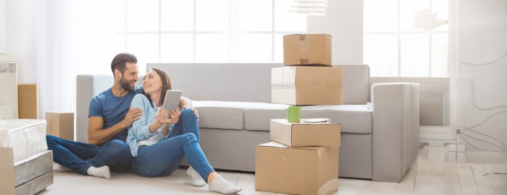 Paar sitzt im Wohnzimmer zwischen Umzugskartons